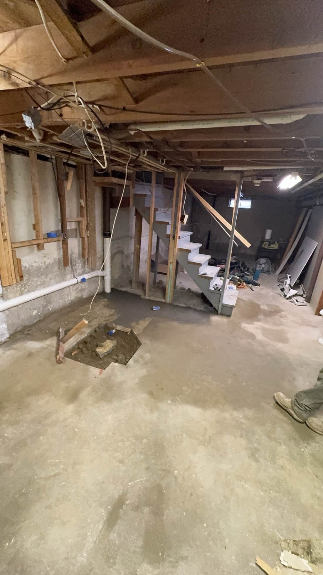 Basement floor area prepped for plumbing near the stairway