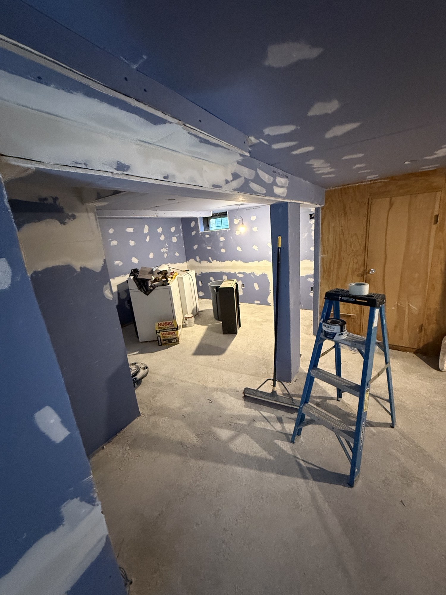 Basement room with unfinished taped drywall walls and bare concrete floor