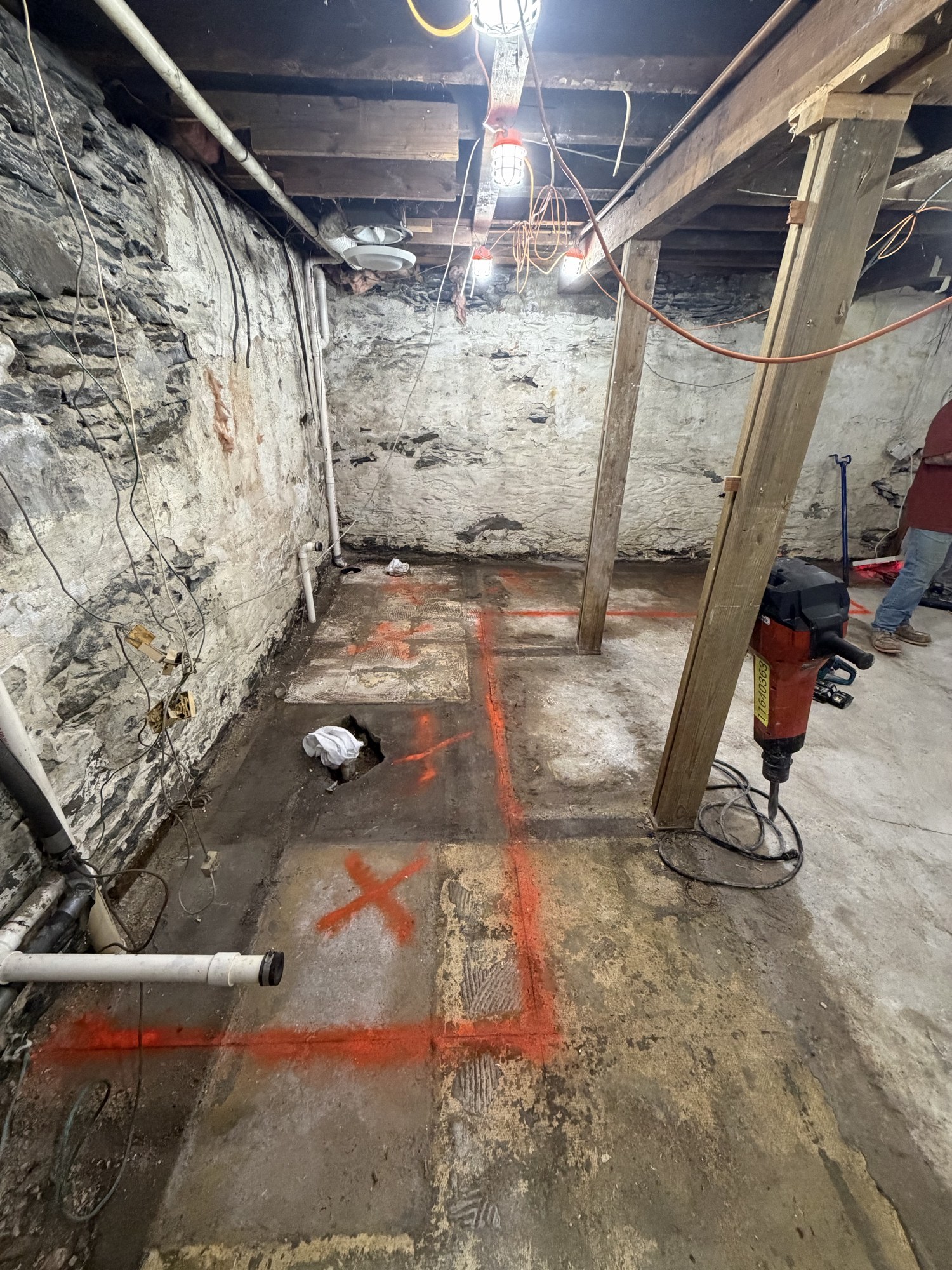 Basement crawl space with footing locations marked and jackhammer staged