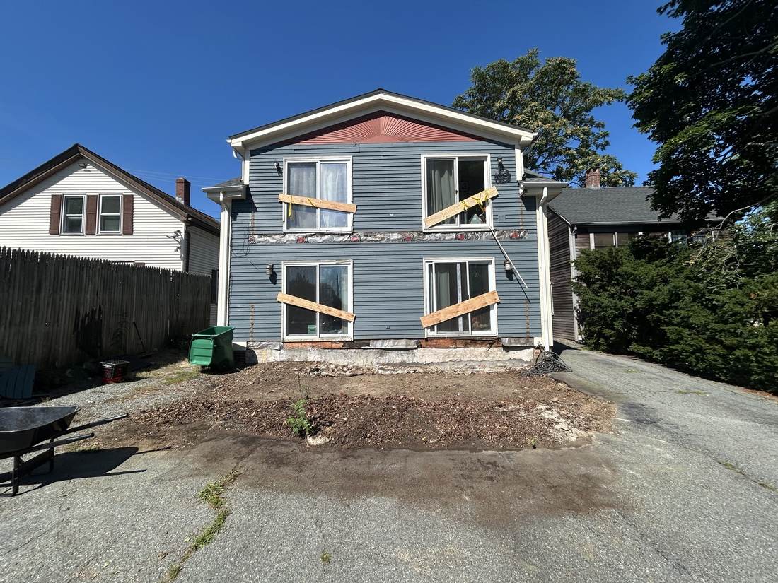 Rear of the same house, with siding and window repairs in progress