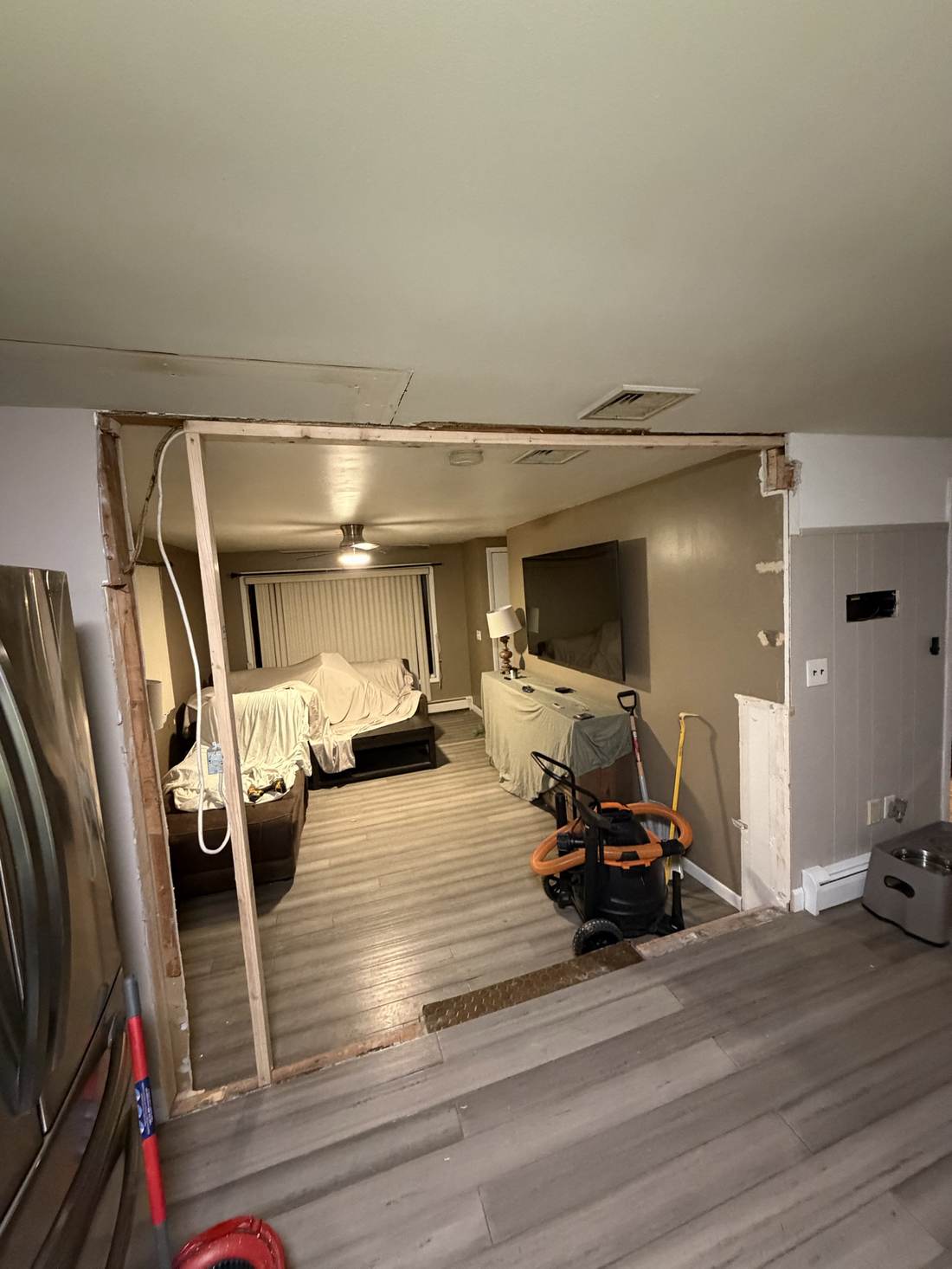 New open doorway between kitchen and living room with fresh flooring